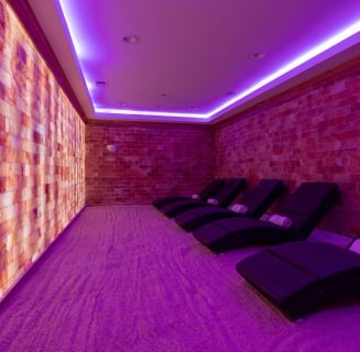 room with purple light and salt walls with a number of large lounge chairs