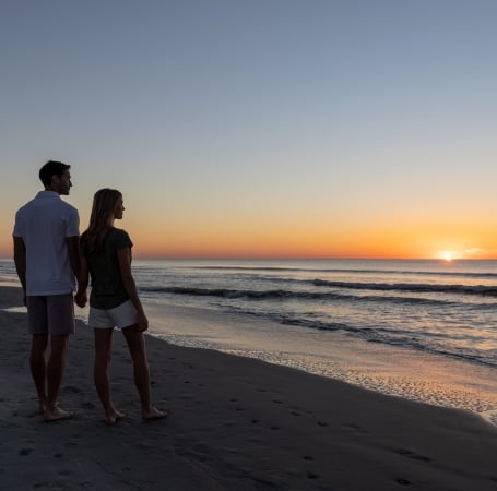 couple standing on the beach at sunrise