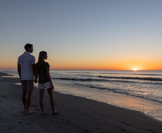 couple standing on the beach at sunrise